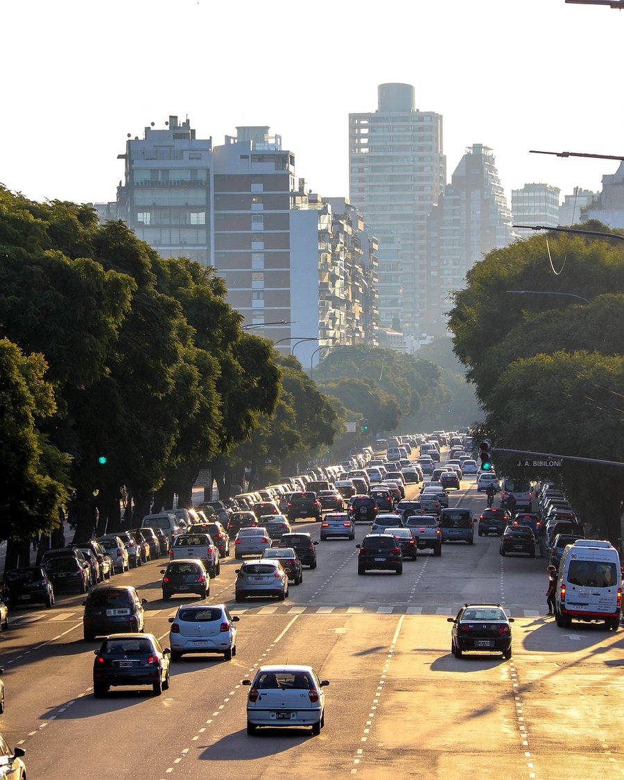Breite Avenida mit Baumreihen und Abendverkehr in Buenos Aires
