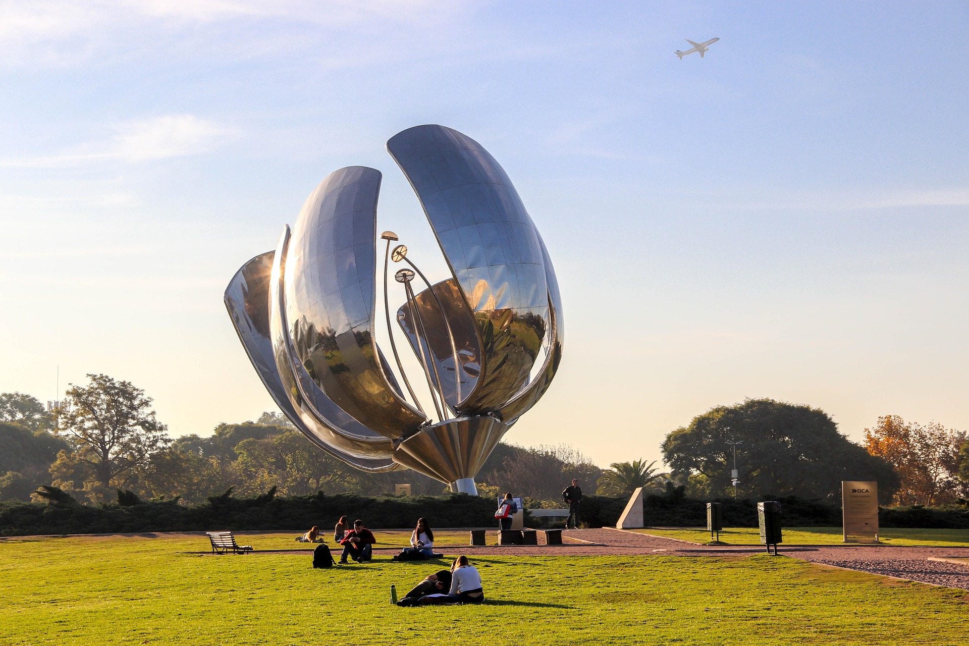 Floralis Genérica im Abendlicht, ein Flugzeug am Himmel